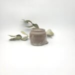 Underside view of a handcrafted dark stoneware mini pitcher showing the unglazed foot ring and maker's mark