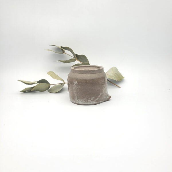 Underside view of a handcrafted dark stoneware mini pitcher showing the unglazed foot ring and maker's mark
