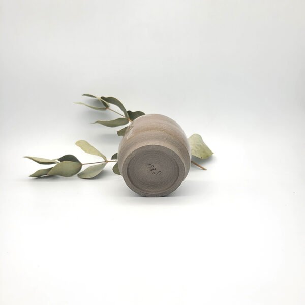 Underside view of a handcrafted dark stoneware mini pitcher showing the unglazed foot ring and maker's mark