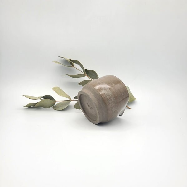 Underside view of a handcrafted dark stoneware mini pitcher showing the unglazed foot ring and maker's mark